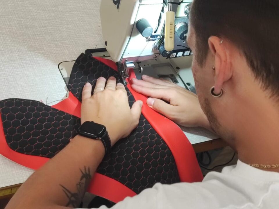 Cucitura del bordo rosso di una sella racing alla macchina da cucire industriale