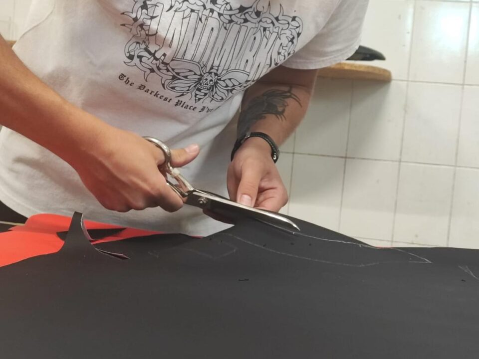 Taglio della finta pelle nera con forbici sartoriali per il rivestimento di una sella