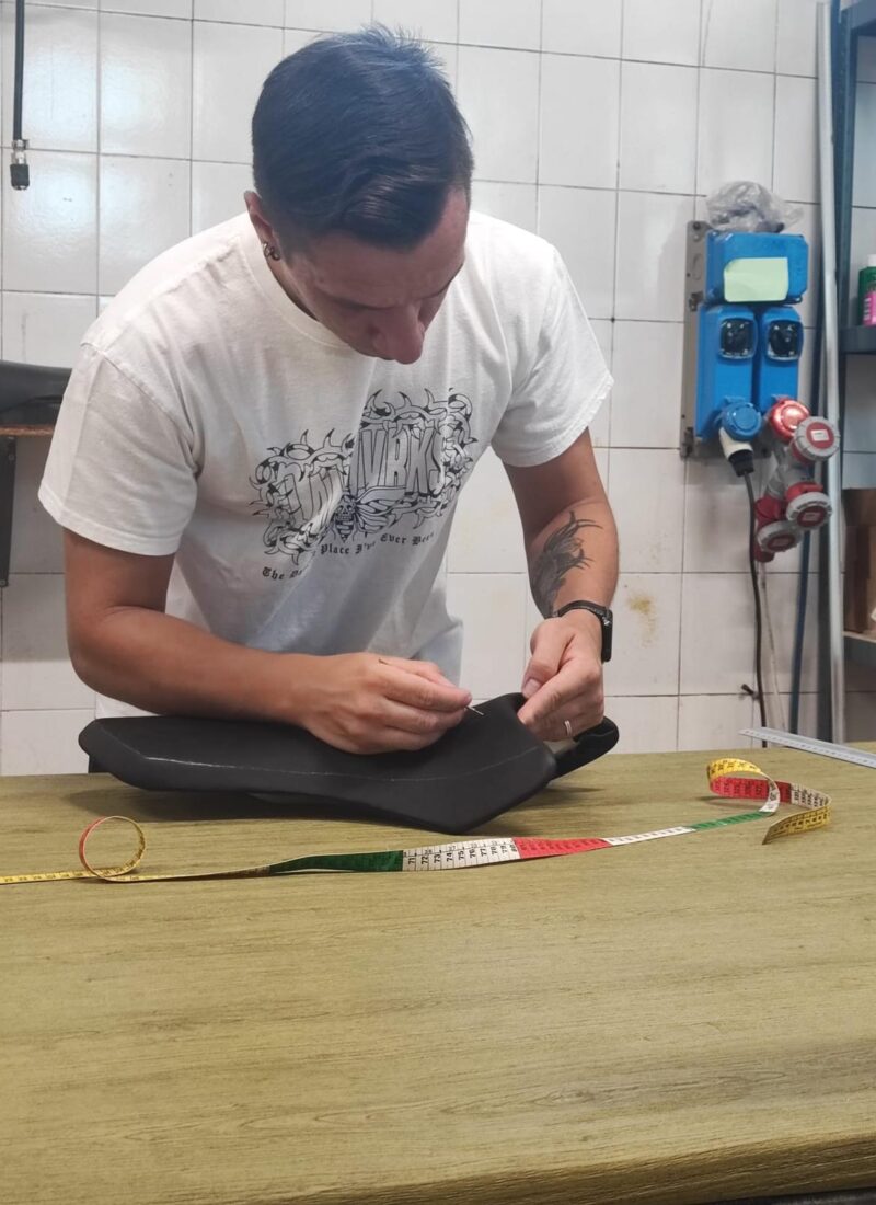 Marco Pizzinato prende le misure di una sella moto sul banco da lavoro
