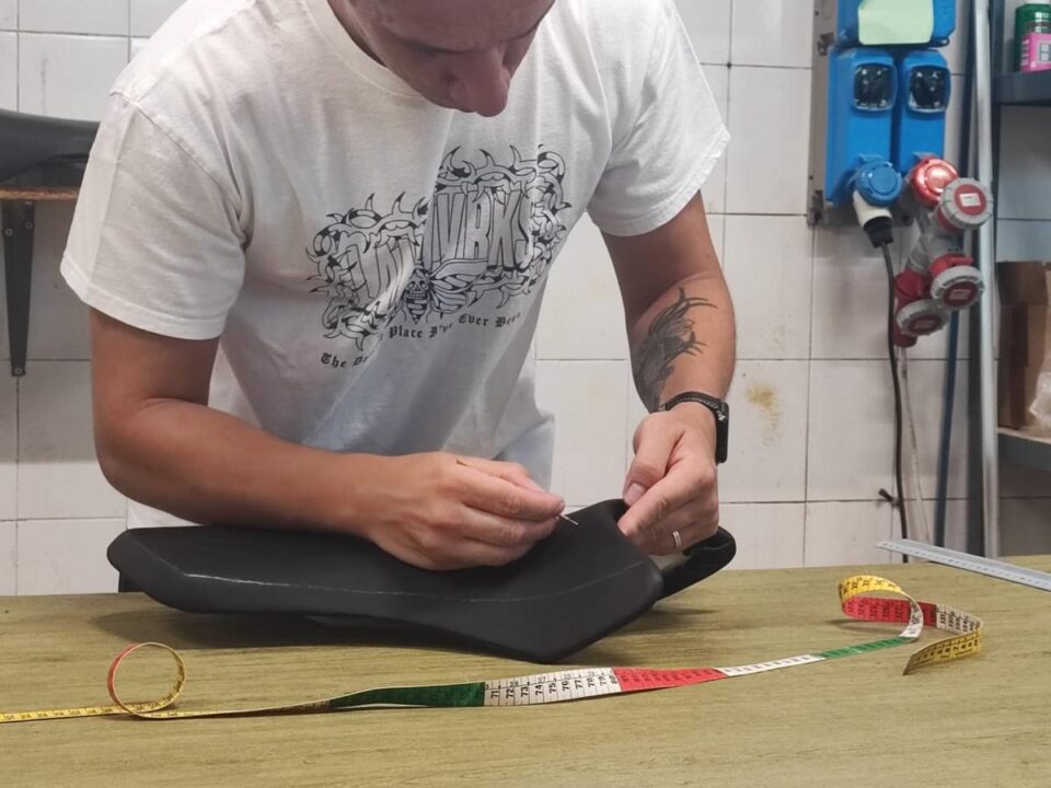 Marco Pizzinato prende le misure di una sella moto sul banco da lavoro